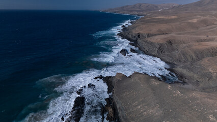 This is a high-angle aerial view of a coastline, showing the striking contrast between the ocean and the land.
