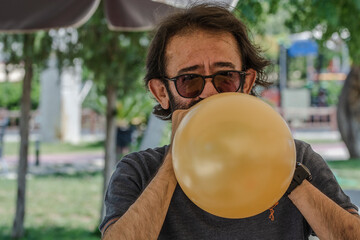 Man with glasses blowing up a balloon