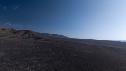 `Desert Track Through Volcanic Hills Under Clear Sky – Remote Arid Landscape