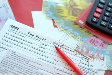 Swiss franc banknotes and tax form with pen. The current francs money bills lies on tax return form