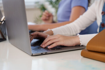 Hands typing laptop keyboard during student project teamwork classroom study assignment learning education youth childhood cooperation technology collaboration