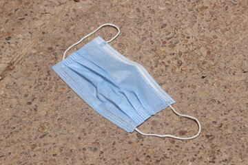 blue surgical mask laying on the ground