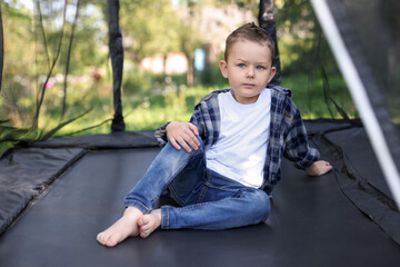 Cute little boy posing on black trampoline outdoors