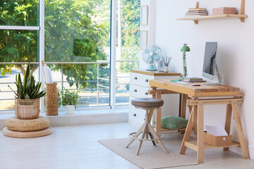 Home workspace. Modern computer and stationery on wooden desk near window indoors