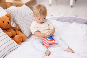 Fototapeta premium Cute little child with flag of USA on bed at home