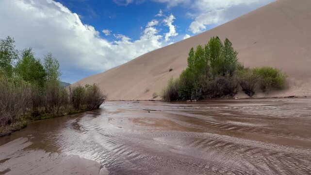 Medano Creek river landscape Great Sand Dunes National Park Sangre de Cristo range Rocky Mountains spring summer sunny clouds blue sky Colorado unique magical large amounts of sand dune windy pan