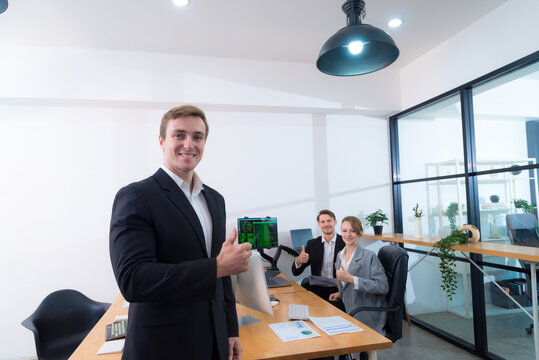 Professional office environment with three individuals showcasing teamwork and positivity. man suit gives thumbs up, while two colleagues background also express approval. modern workspace