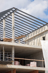 Obraz premium Construction of a modern building with steel framework and concrete structure in progress on a sunny day