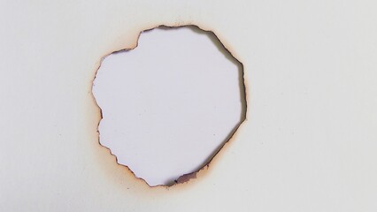Close up of fire burned hole on white paper background. White paper burns. Burnt paper. A piece of...