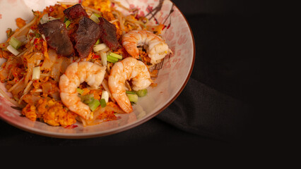 Stir fried kwetiau with shrimp and lapchiong. Served on brown stone plate. Isolated from black background. Perfect for recipe, article, catalogue, or commercial purpose