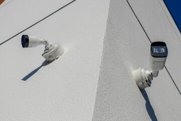 Two security cameras are mounted on the corner of a building, providing surveillance coverage in a...