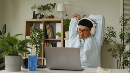 Asian man stretching after working at his home.