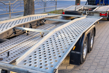 Large transport trailer with perforated surface and ramps parked in a city environment, showcasing...