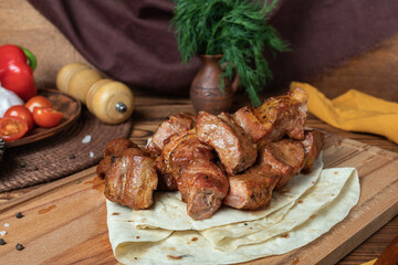 Grilled shashlik kebabs served on flatbread with vegetables in rustic style
