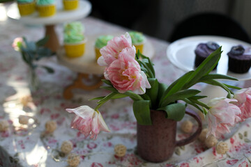 Decorated table with flowers and colorful cupcakes in background