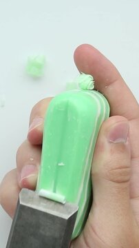 Hands hold a green soap bar while a blade slices through it, creating satisfying chunks and shavings during relaxing soap cutting ASMR session