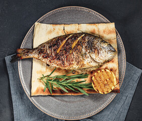 Grilled fish served whole on flatbread with rosemary and lemon garnish