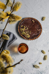Chocolate tart with pistachio crust and tea cup on rustic surface