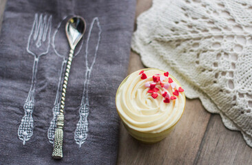Dessert cup with frosting topped with pink and red heart sprinkles
