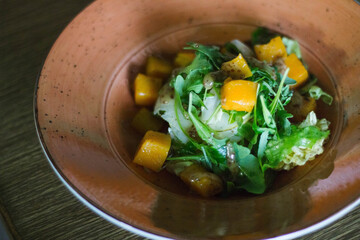 Fresh mango salad with leafy greens served in rustic bowl