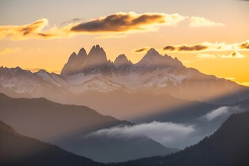 Windows 11 Wallpaper: Golden sunrise lighting rugged mountain peaks above forest with soft clouds and warm glow in early morning view