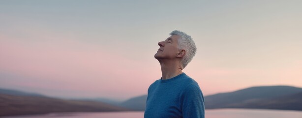 The contemplative man gazing at the serene sunset over the lake.