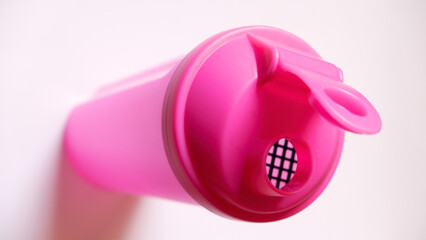 Close-up shot of a pink protein shaker placed on a white surface, ideal for fitness, health, and...