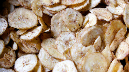 Close-up shot of crispy banana chips filling the entire frame, showing texture and golden color, perfect for food backgrounds and snack concepts.