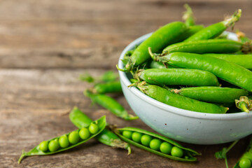 Fresh green pea pods with green peas on a wooden background. Sweet green peas. Green pea beans...