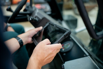 Hands with tablet in machinery cabin symbolizing innovation, digital transformation, and the balance between human skill and machine intelligence in shaping the future of smart construction © K