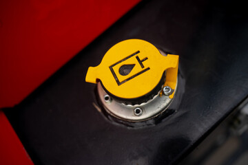 Close-up of yellow hydraulic oil cap on industrial machinery, symbolizing maintenance, lubrication,...