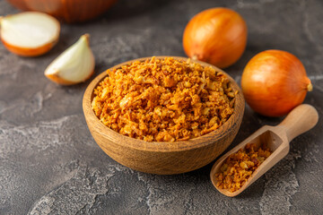 Crispy fried onions in a bowl on a wooden table. Roasted Onions. Seasoning for dishes. Spices....