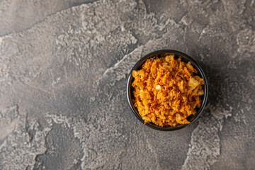 Crispy fried onions in a bowl on a wooden table. Roasted Onions. Seasoning for dishes. Spices. Salad dressing. Space for text. Copy space