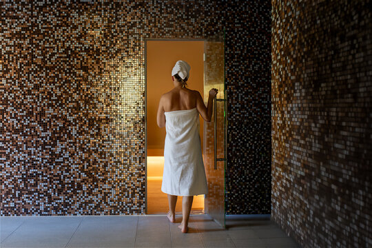A woman enters a luxurious Turkish bath, bathed in a warm and relaxing atmosphere. The walls are covered with splendid mosaics that reflect the light. An oasis of well-being.