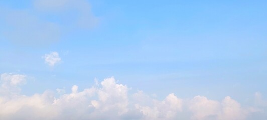Fluffy white cumulus clouds in clear blue sky. Big and fluffy white clouds in a bright blue sky. Large thin clouds floating in the sky form rain clouds. Aerial view of cloudscape on sunny day.