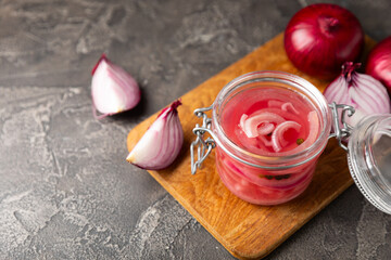Pickled onions in a glass jar on the table. pickled red onion. Vegetarian spicy dish. Delicious homemade marinated pickled purple onions . Space for text. Copy space.