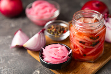 Pickled onions in a glass jar on the table. pickled red onion. Vegetarian spicy dish. Delicious homemade marinated pickled purple onions . Space for text. Copy space.