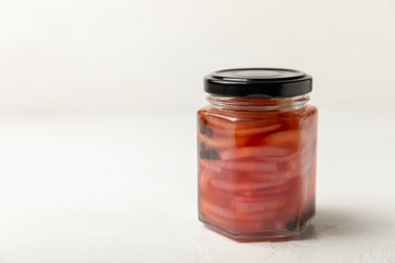 Pickled onions in a glass jar on the table. pickled red onion. Vegetarian spicy dish. Delicious homemade marinated pickled purple onions . Space for text. Copy space.