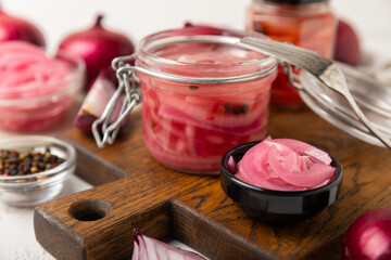 Pickled onions in a glass jar on the table. pickled red onion. Vegetarian spicy dish. Delicious homemade marinated pickled purple onions . Space for text. Copy space.