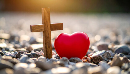 Wooden Christian cross on gravel ground with red heart. Strong religious symbolism of divine love