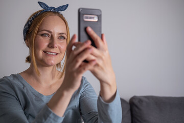 Middle aged millennial woman holding smartphone, social media, communication and modern technology