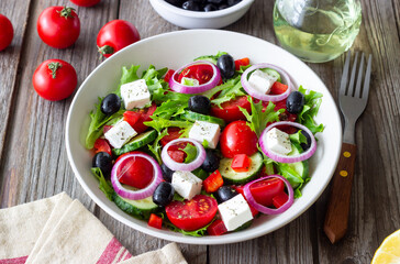 Greek salad with feta cheese, tomatoes, onion, cucumbers, peppers and olives. Healthy eating. Vegetarian food.
