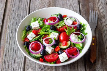 Greek salad with feta cheese, tomatoes, onion, cucumbers, peppers and olives. Healthy eating. Vegetarian food.