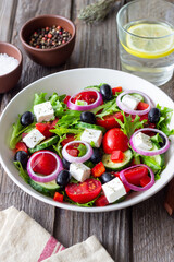 Greek salad with feta cheese, tomatoes, onion, cucumbers, peppers and olives. Healthy eating. Vegetarian food.