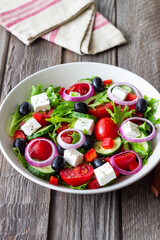 Greek salad with feta cheese, tomatoes, onion, cucumbers, peppers and olives. Healthy eating. Vegetarian food.