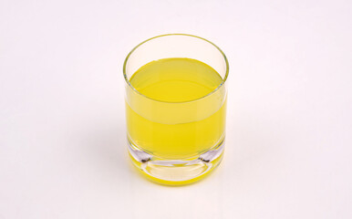 Glass of fresh yellow juice on white background. A clear glass filled with bright yellow juice placed on a clean white surface. Perfect for concepts of freshness, health and nutrition.