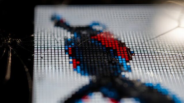 Electronic screen displaying digital art with pixelated shapes in shades of red and blue. Electronic screen art reveals an abstract aesthetic through its vivid colors.