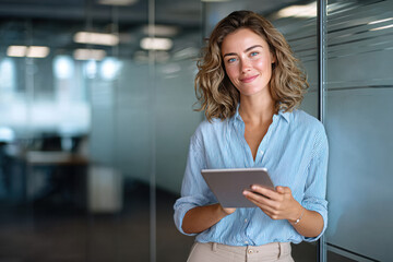 Confident businesswoman using tablet in modern office, female professional with digital technology at workplace - young business woman with tablet computer