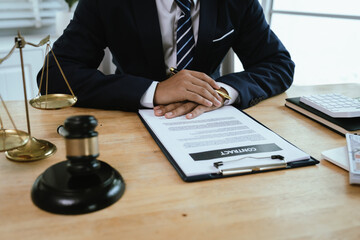 A professional male lawyer sits at a desk with documents and gavel, symbolizing law, judgement, authority, justice, and legal expertise.