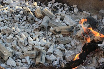 Ash, embers, briquettes, and burning charcoal in a fire pit.